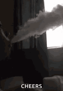 a person is blowing smoke out of a pipe in a room .