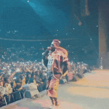 a man in a colorful outfit is singing into a microphone in front of a crowd of people