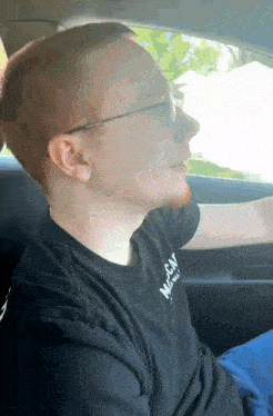 a man in a car wearing a black shirt that says mccay