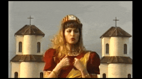 a woman in a red and gold dress is standing in front of two churches