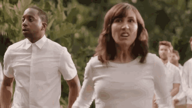 a man and a woman in white shirts are running in a line .