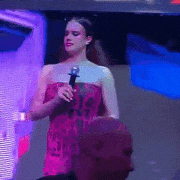 a woman in a pink dress is holding a microphone in front of a man