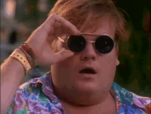 a man wearing sunglasses and a colorful shirt is looking through his glasses .