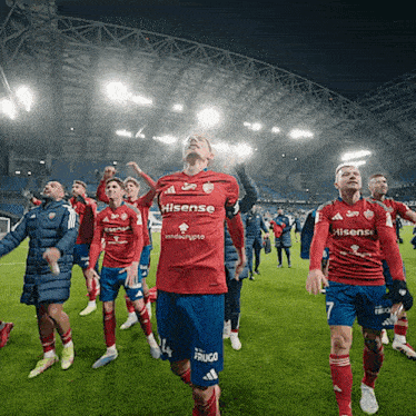 a soccer player wearing a hisense jersey stands on the field with his teammates