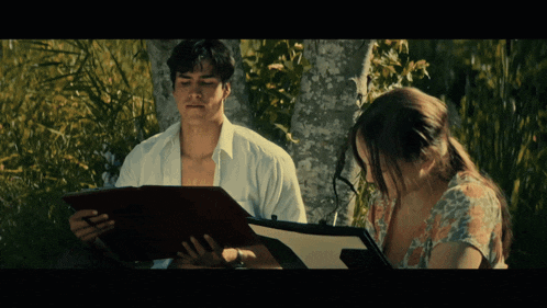 a man and a woman are looking at a folder together
