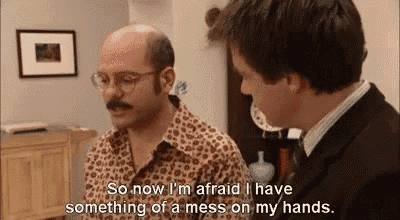 two men are talking to each other in a living room . one of the men is bald and has a mustache .