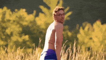 a shirtless man in blue shorts is standing in a field