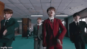 a group of men in suits and ties are dancing in a room .