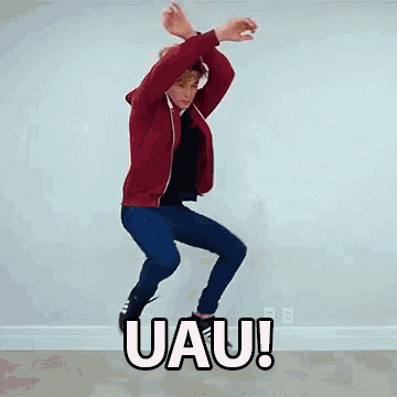 a man in a red jacket is jumping in the air with the word uau written on the floor