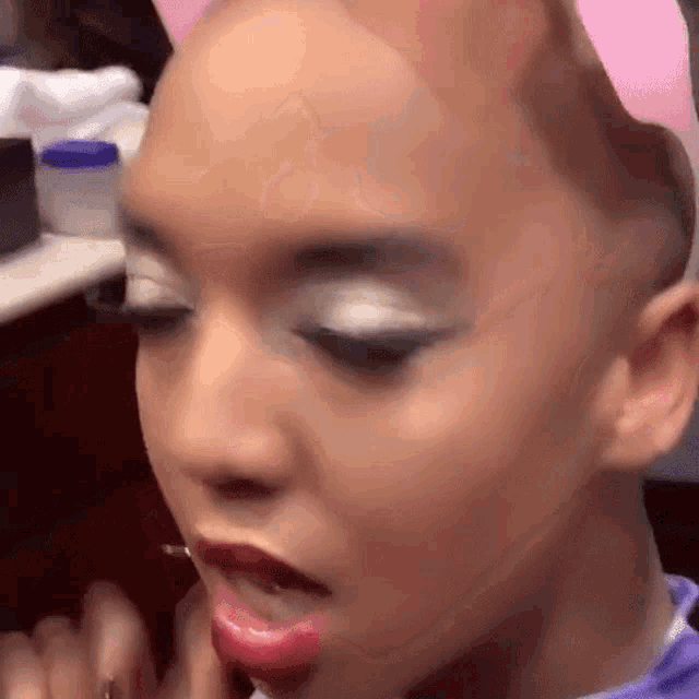 a woman with a pink bow on her head is applying makeup .