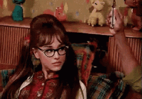 a woman wearing glasses is sitting on a couch and holding a lighter .