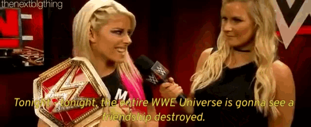 two women are standing next to each other and one of them is holding a wrestling belt