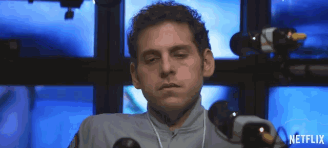 a man in a police uniform is sitting in front of a bunch of monitors .