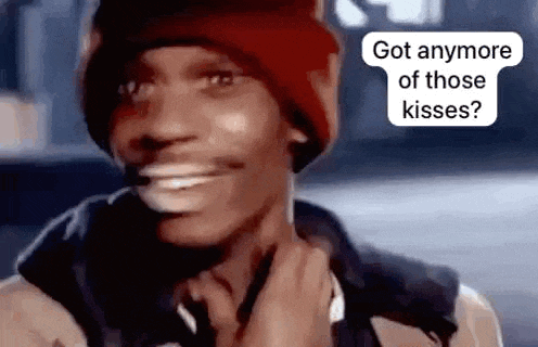 a man wearing a red hat and a black jacket is smiling and talking about kisses .