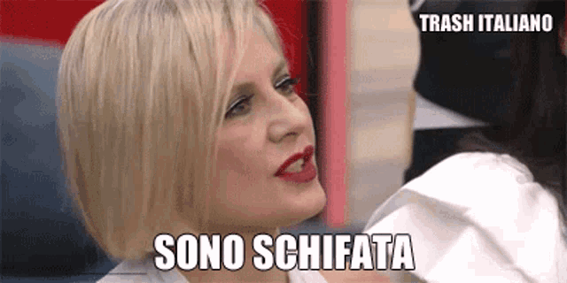a woman with blonde hair and red lipstick is making a funny face while sitting in a chair .