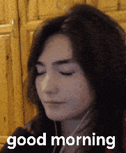 a woman with her eyes closed is wearing ear buds and says good morning
