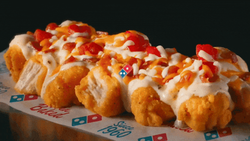 a domino 's pizza covered in toppings is sitting on a piece of paper that says baked since 1960