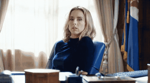 a woman is sitting at a desk in front of a window in a room .