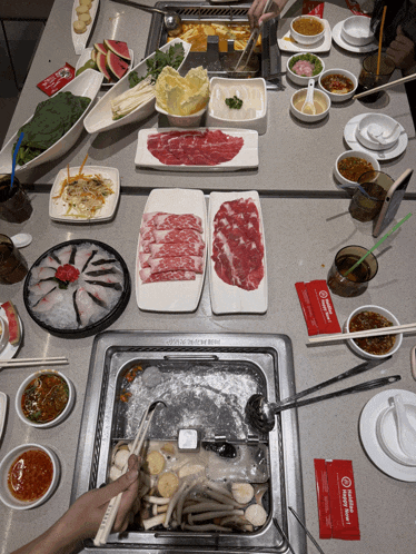 a hot pot is being cooked on a table with plates of food