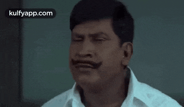 a man with a mustache is making a funny face while holding his hand to his face .