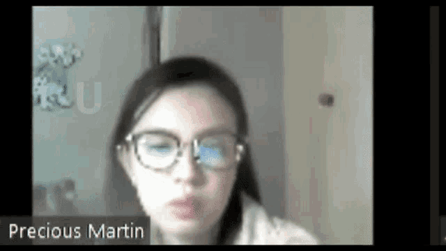 a woman wearing glasses is on a zoom call with the name precious martin