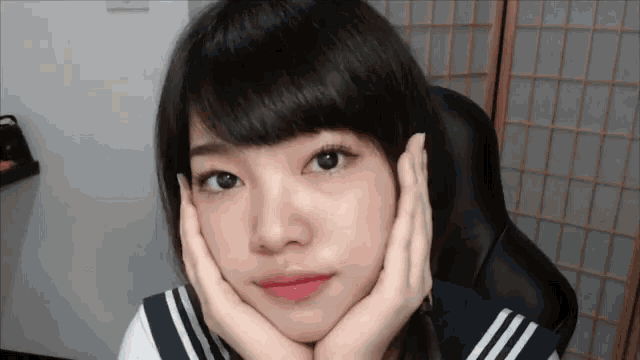 a girl with her head resting on her hands looks at the camera