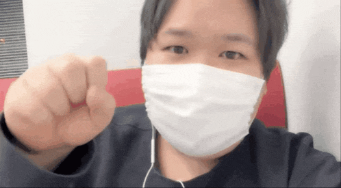 a man wearing a face mask is giving a thumbs up
