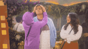 a woman in a purple hoodie is touching another woman 's forehead