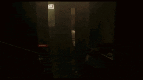 a person is walking through a dark room with a fire extinguisher on the wall