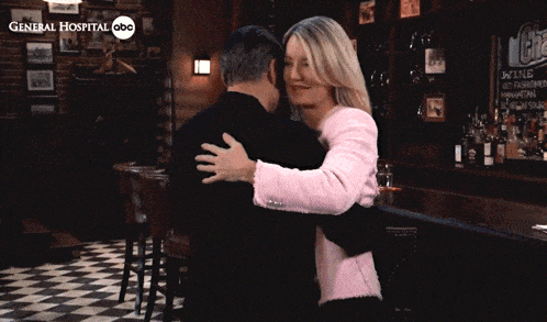 a man and a woman hugging in front of a sign that says general hospital abc