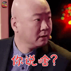 a bald man in a suit and tie is making a funny face with chinese writing on his face .