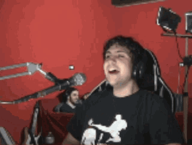 a man wearing headphones is sitting in front of a microphone laughing