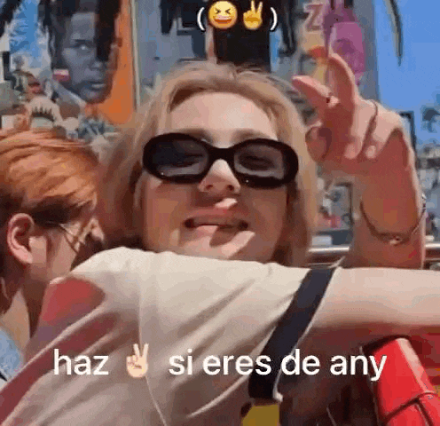 a woman wearing sunglasses is giving a peace sign while sitting on a roller coaster .