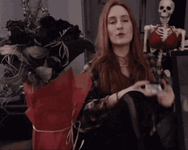 a woman with red hair is holding a bouquet of black roses
