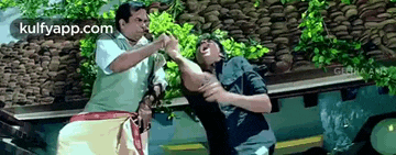 two men are fighting in front of a building .