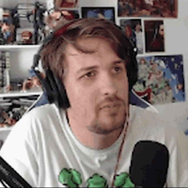 a man wearing headphones and a white shirt is sitting in front of a microphone .