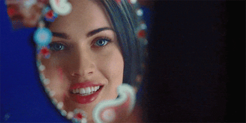a close up of a woman looking at herself in a mirror and smiling
