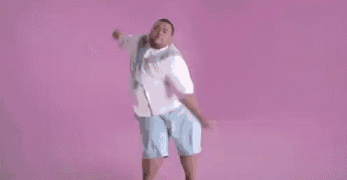 a man in a white shirt and blue shorts is dancing in front of a pink background .
