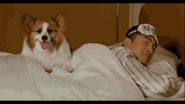 a man wearing a sleep mask is sleeping with a dog
