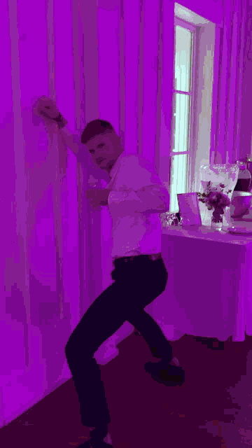 a man dancing in front of a pink wall