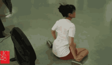 a girl sits on the floor next to a fan with the number 48 on the bottom