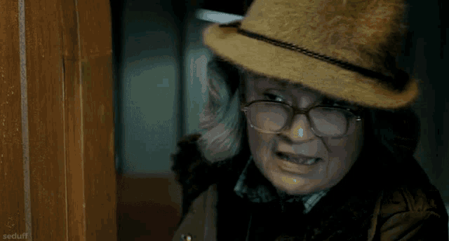 an older woman wearing a hat and glasses is smiling and looking at the camera