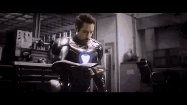 a man in a iron man suit is sitting in a chair in a garage .