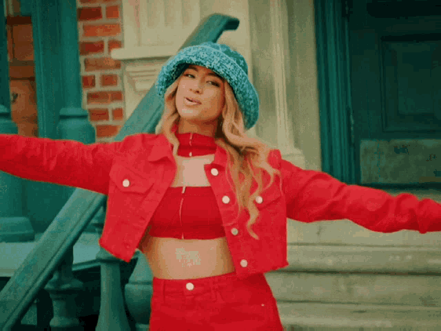 a woman wearing a red jacket and a blue hat is standing on a set of stairs