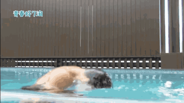 a man is swimming in a pool with chinese writing on the side