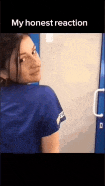 a woman in a blue scrub top is standing in front of a door and looking over her shoulder .