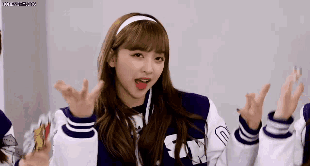a girl in a purple and white baseball jacket is making a funny face .