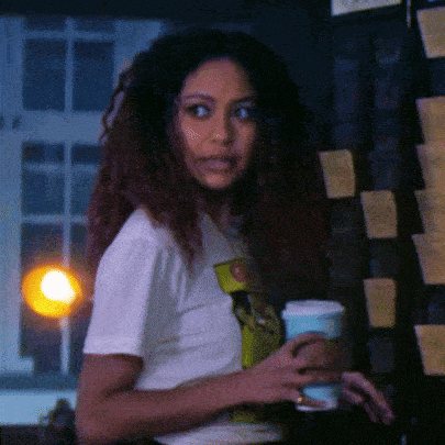 a woman in a white t-shirt holds a cup of coffee