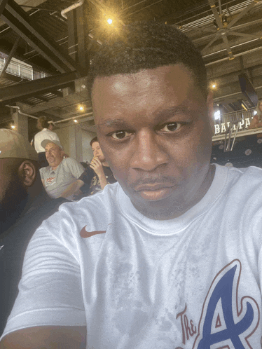 a man wearing a white shirt with the letter a on it takes a selfie