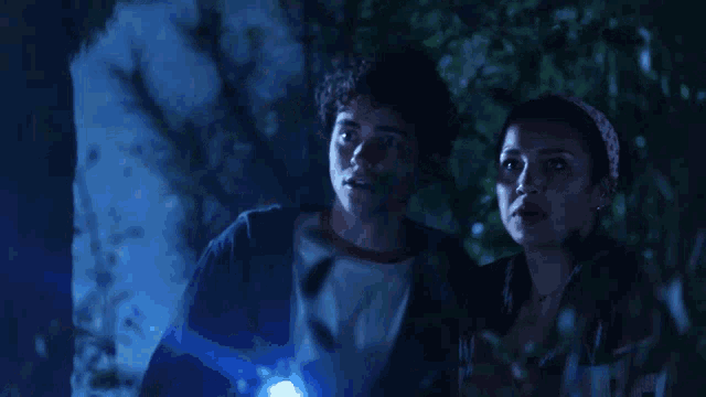 a man and a woman are looking through trees at something